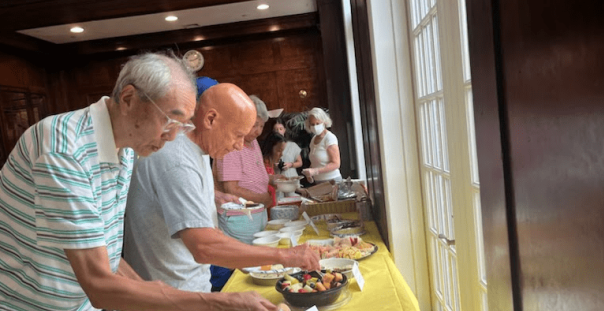 a group of people standing around a table with plates of food