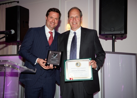 two men standing next to each other holding an award