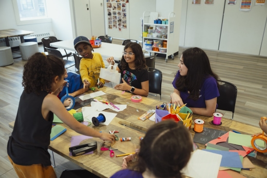 a group of children sitting around a wooden table