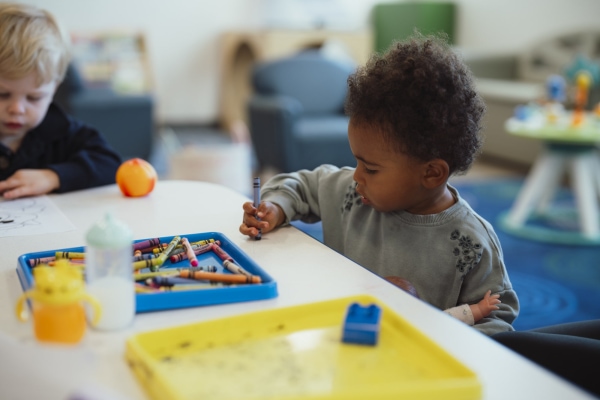 a child sitting at a table with crayons image