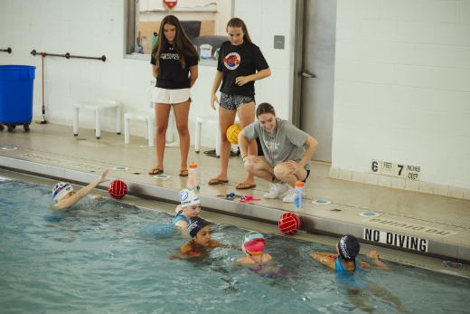 a group of people standing around a swimming pool