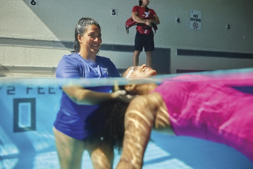 a woman swimming in a pool with a man standing behind her