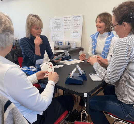 a group of women sitting around a table playing cards