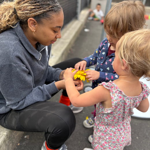 two young children looking at a flower at school
