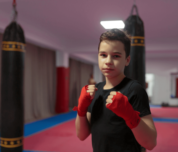 a young boy wearing boxing gloves in a gym