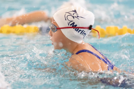 a woman swimming in a pool wearing a hat